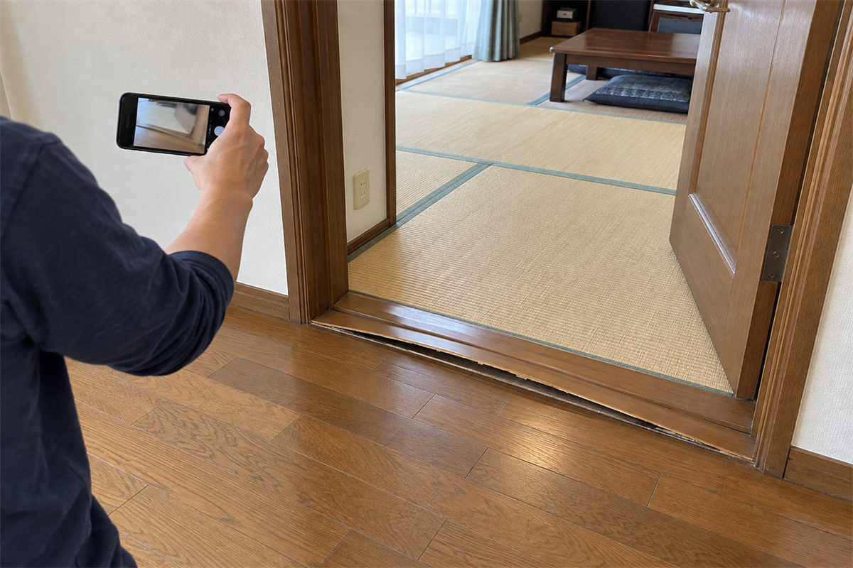 見切り材の浮いた出入口全体を安全な位置から撮影する様子